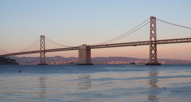 Bay Bridge at sunset with a ferry going by